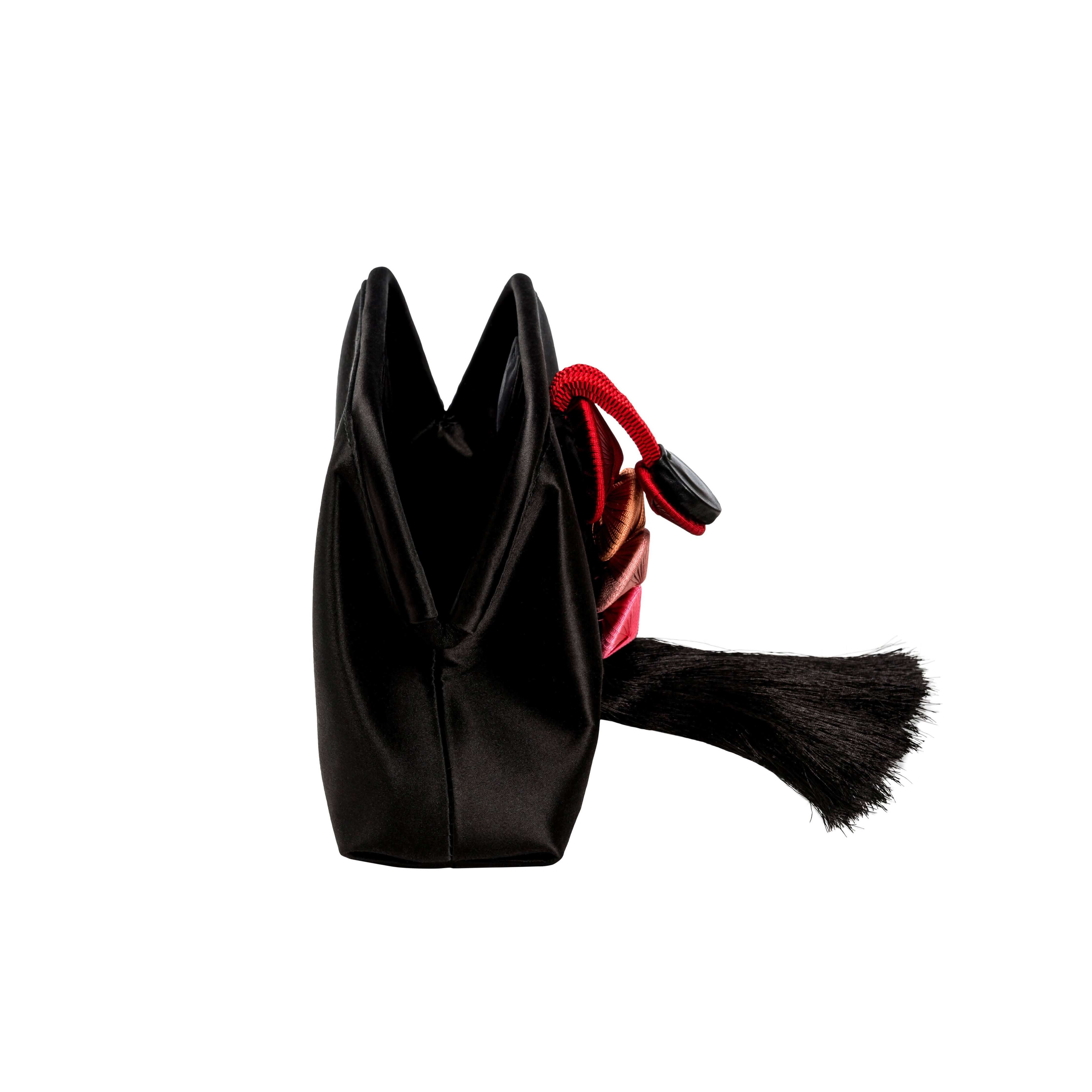 Alessa Black Pouch Bag showcasing its modern design and silk satin texture with a striking tassel detail.