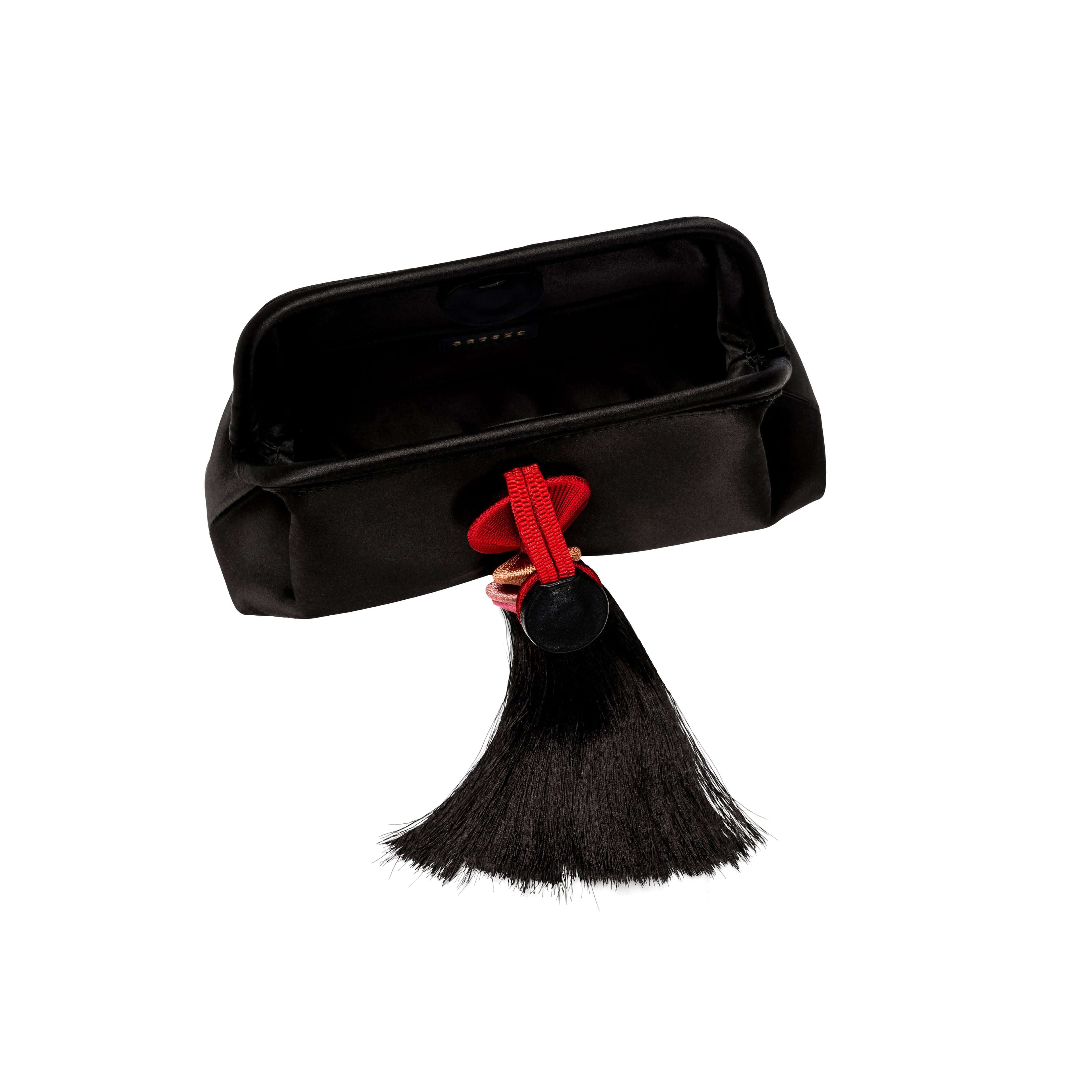 Alessa Black Pouch Bag showcasing a silk satin finish with a unique tassel and thread-wrapped design.