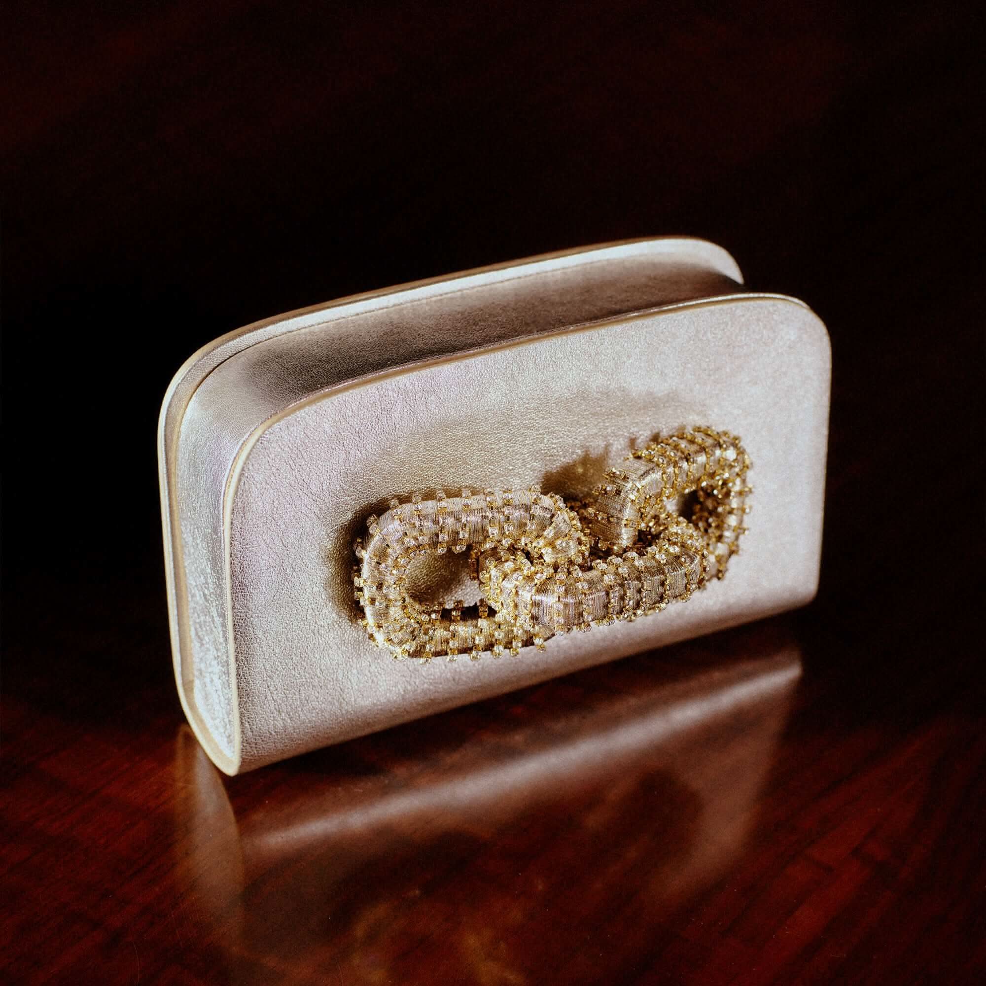 Elegant Catena Sahara & Glam two-sided clutch featuring intricate beadwork on a soft beige background.