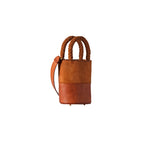 Rovena Camello Mini Bucket Bag in brown leather with braided handles and adjustable strap, stylish and versatile accessory.