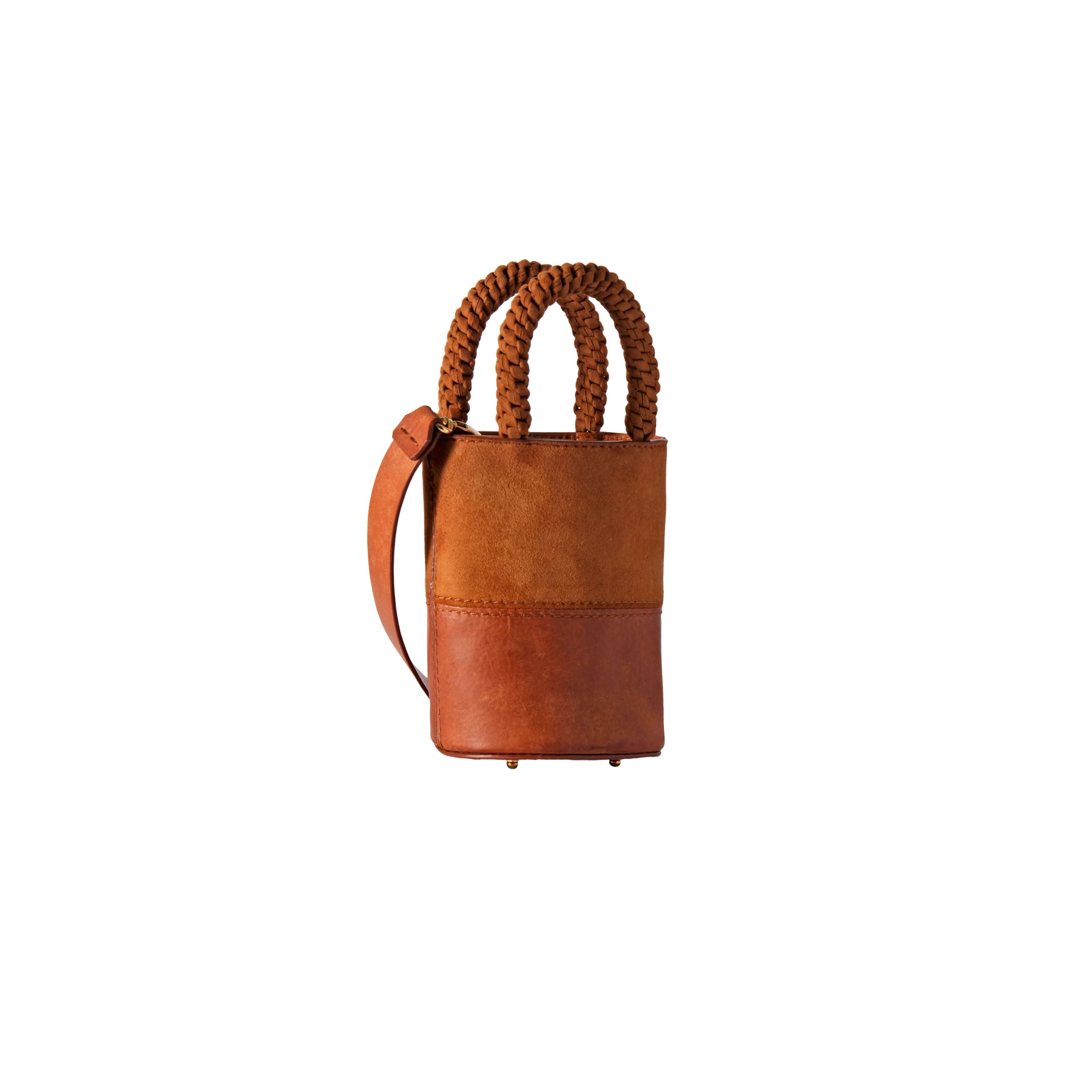 Rovena Camello Mini Bucket Bag in brown leather with braided handles and adjustable strap, stylish and versatile accessory.